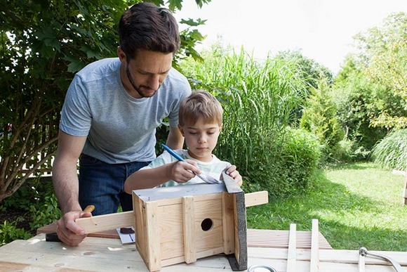 Person und Kind bauen ein Vogelhaus